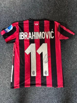 Zlatan tröja - Tjena! En Zlatan tröja med Ac Milan märke. Tröjan är inte riktig match tröja då han röker en cigarr på framsidan av tröjan. Autografen på ryggen är en replika. Storlek S-M och är i mycket bra skick.