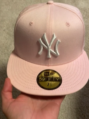 New Era 59FIFTY New York Yankees Pink Fitted Cap - Säljer en New Era 59FIFTY New York Yankees keps i ljusrosa färg. Kepsen är fitted (ej justerbar) och har storlek 7 1/2 (59.6 cm). Klassisk Yankees-logga framtill i vitt. Perfekt skick, endast använd ett fåtal gånger. Passar både dam och herr. 