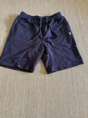 Marinblå shorts från Polo Ralph Lauren - Snygga marinblå shorts från Polo Ralph Lauren med dragsko i midjan och diskret logga broderad på vänster ben. Tillverkade i mjuk bomull, perfekta för sommardagar. Klassisk passform och två sidofickor.
