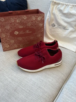  Loro Piana flexy walk - Äkta! Snygga vinröda sneakers från Loro Piana med stickad ovandel och vita sulor med bruna detaljer. Skorna har rund tå, snörning och diskret logga på hälen. Perfekta för dig som gillar exklusiv och stilren design. Låda eller påse ingår ej