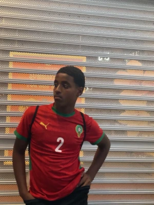 Papi reyna  - Säljer en röd fotbollströja från Puma med Marockos landslagsemblem på bröstet och nummer 2 tryckt framtill. Tröjan har gröna detaljer vid krage och ärmslut samt gula Puma-loggor. Perfekt för dig som älskar fotboll och vill stötta Marocko.