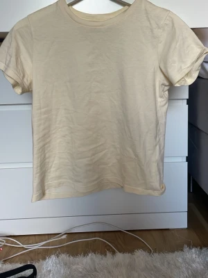Beige basic t-shirt i bomull - En enkel och stilren beige t-shirt i mjuk bomull. T-shirten har rund halsringning och korta ärmar, perfekt för en clean och avslappnad look. Passar till allt och är ett måste i garderoben.
