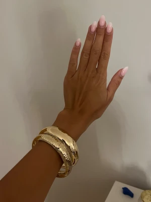 Guld armband  - Två superfina stela guldarmband i rostfritt stål. Superfina men kommer ej till användning. Aldrig använda! Ett slätt och ett med hamrar mönster. Priset gäller för båda tillsammans! 