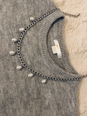 Silverfärgat halsband med pärldroppar - Snyggt halsband i silverfärgad rostfritt med kedja och hängande droppformade pärlor. Perfekt accessoar för att lyfta din outfit med en trendig och elegant touch. Passar till många olika stilar och är lätt att matcha.