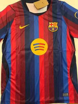 Lamine Yamal Barcelona 26/27 tröja - Fotbollströja i helt nytt och oanvänt skick med tag kvar. Detaljrik design och bekvämt material som passar både till match och vardag. Detta är en inofficiell version av modellen. Storlek M