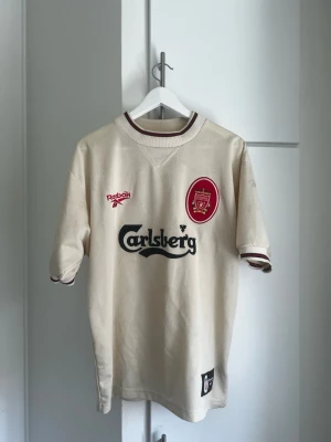 Liverpool 1996/97 Away Reebok Carlsberg Original Made in UK – M - Säljer en äkta Liverpool FC bortatröja från säsongen 1996/97.  Original Reebok med Carlsberg-sponsor.  * Made in UK * Storlek M * Mycket fint vintage-skick * Inga hål eller större skador  En klassisk 90-talströja som blivit mycket eftertraktad bland samlare och Liverpool-supportrar.  