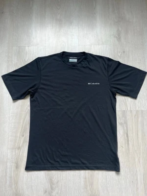 Columbia Omni-Wick T-shirt – Storlek S - Säljer en svart t-shirt från Columbia med diskret logga på bröstet. Tillverkad i ett lätt och snabbtorkande syntetmaterial med Omni-Wick-teknologi som transporterar bort fukt. Klassisk passform och rund halsringning, perfekt för aktiva dagar. Pris kan diskuteras 