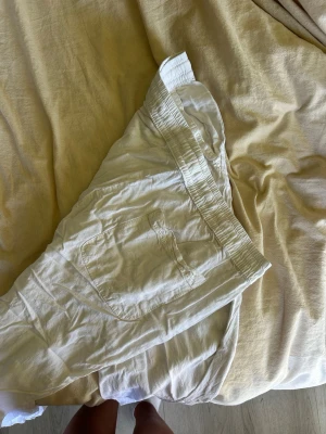 Vita linnebyxor med resårmidja - Säljer ett par vita linnebyxor med avslappnad passform och resår i midjan. Byxorna har snedställda fickor fram och en bakficka. Perfekta för sommardagar och riktigt sköna att bära tack vare det tunna linnetyget. De är inte strykta så därför de kanske ser värre ut, men bara att stryka 