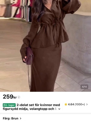 Brunt 2-delat set med volangtopp - Säljer ett brunt 2-delat set med långärmad volangtopp och figurnära lång kjol. Toppen har knytning i midjan och vida ärmar för en trendig look. Setet är i ett mjukt, lätt tyg som ger en snygg siluett. Perfekt för dig som gillar stilrena och moderna outfits.
