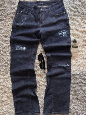 Bootcut Jeans - Handgjorda Bootcut Jeans – Unik Design – Väldigt bra skick  Unika jeans som jag själv gjort om till bootcut och lagt till egna slitningar samt designdetaljer både fram och bak. Ett riktigt snyggt och personligt par som sticker ut och inte finns i någon annan garderob.  Jeansen är i väldigt bra skick och ser knappt använda ut. Perfekta för dig som gillar vintage, Y2K och streetwear.  📏 Mått: • Midja: 40 cm • Längd: 103 cm • Benöppning: 22 cm  