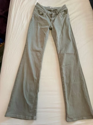 Gröna bootcut jeans från Nelly - Snygga gröna bootcut jeans från Nelly med låg midja och klassiska fem fickor. Jeansen har vida ben och är tillverkade i ett mjukt bomullsmaterial med lite stretch för extra komfort. Perfekta för dig som gillar en avslappnad men trendig stil. Använda max fem ggr. 