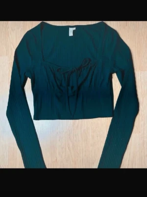 Nelly svart ribbad crop top med  fyrkantig halsringning och söt knytning • Y2K • Coquette • Stretch • Strl S -  Snygg svart ribbad croppad topp från Nelly med fyrkantig urringning och knytning framtill. Stretchigt material som sitter bekvämt och ger en smickrande passform. Perfekt till jeans, kjol eller lager-på-lager. Mycket fint skick.  🖤 Storlek: S 📏 Mått: Längd ca 41 cm, byst ca 82 cm, midja ca 68 cm 🧵 Material: 64 % återvunnen polyester, 33 % viskos, 3 % elastan  Jag erbjuder gärna paketpris vid köp av flera varor! 