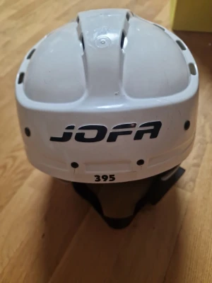 Vit hockeyhjälm från Jofa 395 - Säljer klassisk JOFA 395 ishockeyhjälm i vit. Tillverkad i Sverige, eftertraktad modell bland ishockeyintresserade. Storlek Junior. Mycket bra skick, inga sprickor och aldrig utsatts för allvarlig krock. Galler går att montera på sidorna (ingår ej). Pris: 150 kr 