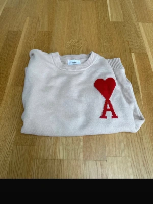 Beige stickad tröja från Ami Paris - Snygg beige stickad tröja från Ami Paris med röd hjärt- och A-logga på bröstet. Tröjan har rund halsringning och ribbade muddar. Perfekt för dig som gillar stilrena plagg med en twist. Jag har även kvitto så skicka vid intresse😍🤩. Det är bara att skriva vid bud, funderingar eller frågor.Priset kan såklart diskuteras det är bara att skriva till mig 😍