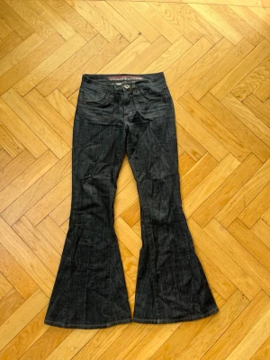 Mörkblå utsvängda jeans - Snygga mörkblå jeans från standards & practices med utsvängda ben och klassisk femficksmodell. Jeansen har kontrastsömmar och en knappgylf. Low waist