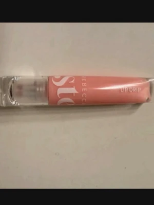 Persikofärgat läppglans Lip Drip - 🌸Säljer ett persikofärgat läppglans med transparent hylsa och applikator. Glanset har en mjuk, glansig finish och kommer i en stilren tub med vit text. Perfekt för dig som vill ha en fräsch och naturlig look.