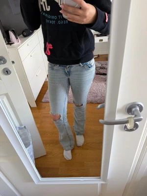 Ljusblå bootcut jeans med hål - Säljer ett par ljusblå bootcut jeans med slitna hål vid knäna och broderade detaljer på bakfickorna. Jeansen har klassisk femficksdesign❤️Knappt använda!