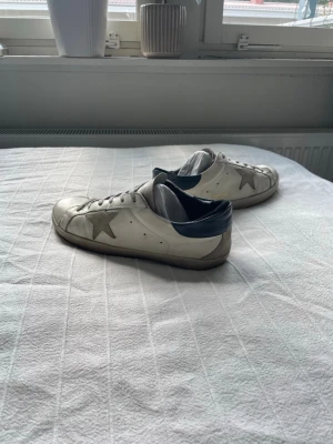 Golden goose sneaker - vita - Snygga och exklusiva Golden Goose sneakers i vitt, perfekta för en stilren och trendig look. Klassisk Golden Goose-design som passar lika bra till jeans som till en mer uppklädd outfit.  👟 Märke: Golden Goose 🎨 Färg: Vit ⭐ Modell: superstars  📏 Storlek:  📦 Skick: bra skick  Golden Goose med den karakteristiska italienska designen och vintage-inspirerade looken.  📩 Skicka gärna meddelande vid frågor eller om du vill ha fler bilder