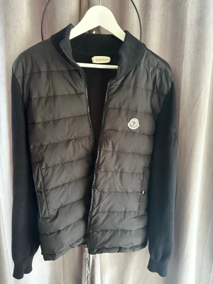 Moncler cardigan  - Säljer min riktigt snygga Moncler cardigan som dessvärre inte passar mig längre. Riktigt clean svart modell med Moncler-loggan på bröstet och stickade ärmar. Storlek M, bra skick med lite mindre användningsspår. Alla tags och QR-kod finns kvar. Säljer endast då den inte passar längre, annars hade jag lätt behållit den. Hör av dig vid funderingar mvh Melwin😊