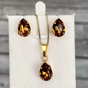 Smyckesset Pear kristall  - Ett set med halsband och stud örhängen. Guldplätterad mässing och kristaller. Pear 14mm Smoked Topaz. Längd 48cm inkl lås och förlängningskedja.  Finns även att få i andra färger på kristallen. Senare bilder visar andra färger som finns i lager.  Jag skickar endast spårbart, samfraktar. Fast pris. Besök gärna mina övriga annonser.  Till mina smycken använder jag kristaller från Preciosa, Aurora och Swarowski.