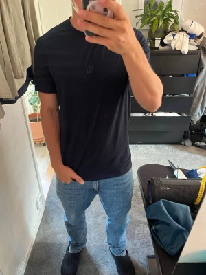 Marinblå Tresanti t-shirt - Snygg t-shirt med rund hals och korta ärmar. På bröstet finns en liten, diskret broderad logga i samma färg som tröjan. Skön passform över både axlar och bröst. Skriv om du har frågor, pris går att diskutera!  