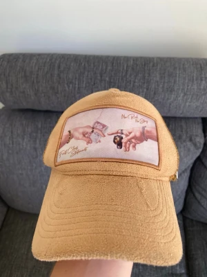 Lyxery keps beige - Säljer en beige keps från LYXERY med mesh på sidorna och en unik patch framtill med motiv av två händer, pengar och klocka samt texten 'No Risk No Story' och 'First Class Support'. Kepsen har böjd skärm och metallogo på sidan. Använt fåtal gånger, bra och snygg keps.