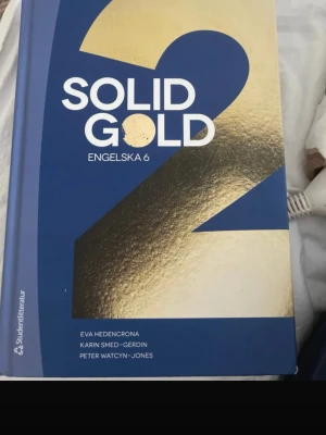 Solid Gold 2 Engelska 6 kursbok - Solid Gold 2 Engelska 6 med blått och guldigt omslag. Boken är inbunden och används ofta på gymnasiet för engelska 6-kurser. Författare är Eva Hedencrona, Karin Smed-Gerdin och Peter Watcyn-Jones.