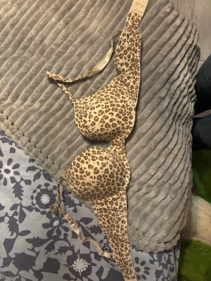 Leopardmönstrad bh - Säljer en snygg leopardmönstrad bh med justerbara axelband. Bh:n har beige botten med bruna fläckar och stängs med hyskor i ryggen. Perfekt för dig som vill ha ett djurmönstrat plagg i garderoben.