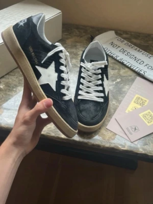 Golden Goose Ballstar svart - Säljer nu dessa snygga och trendiga Golden Goose ballstar i en svart färg med vita detaljer. Skorna är inte använda speciellt mycket och har inga synliga defekter. Storlek 43 TTS. Det som syns på bilderna är det som medföljer. Hör av er vid frågor! 