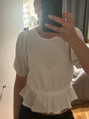 Vit volangblus med puffärm - Supersöt vit blus med puffärmar och volang nedtill.  Från Gina tricot o är i strl S. Endast använt 1 gång så är i princip oanvänd 