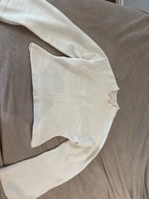 vit stickad  - en stickad tröja med långa ärmar och tajt vid midjan.