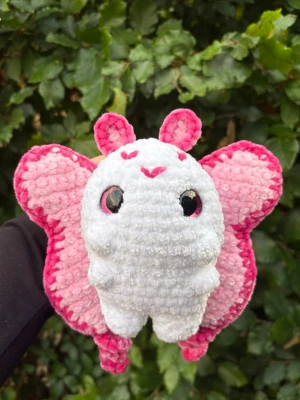 Virkad rosa fjäril🩷 - Supergullig virkat gosedjur i form av en fjäril med stora rosa och vita vingar, vit kropp och söta antenner. Den är gjord i mjukt plyschgarn, perfekt som dekoration eller gosedjur. Rekommenderar dock inte till småbarn då säkerhetsögonen utgör en kvävningsrisk!
