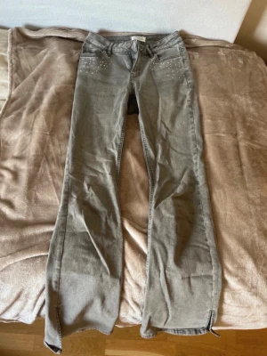Gråa Bootcut Jeans från Lindex - Säljer dessa jättefina bootcut jeans från Lindex med små stenar där fram. De är i stl 170 så ungefär xs-s och är lite korta för mig som är 172 cm, men det beror på hur man vill ha dem. De är i väldigt bra skick kanske bara nån liten tråd där bak, men inget som syns. Hör gärna av er om frågor!💕