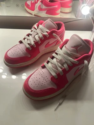 Air Jordan 1 Low rosa och vita sneakers - Säljer mina rosa Nike air Jordan. Använda men i mycket bra skick. Lite tecken på användning t.ex. att sulan har blivit lite smutsig, se bilder. Inga större skador. Hade kunnat tänka mig gå ner lite i pris vid snabb affär. Storlek: 36 Färg: rosa och vit   Skorna säljs eftersom dom blivit för små för mig tyvärr. Skickar snabbt💕