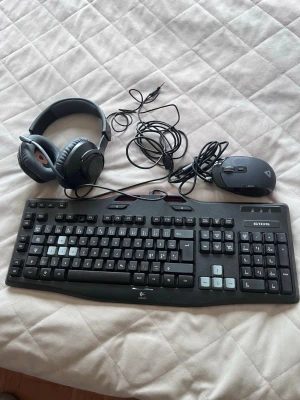 Gamingtillbehör: tangentbord, mus & headset - Säljer ett svart gamingpaket med ett Logitech G105 tangentbord, en Lexip gamingmus och ett par svarta over-ear hörlurar med kabel. Perfekt för dig som vill uppgradera din setup med snygga och funktionella tillbehör.