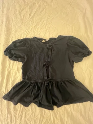 Gina tricot tröja  - Säljer en marin blus med puffiga korta ärmar och flera knyt framtill. Verkligen jättefin 