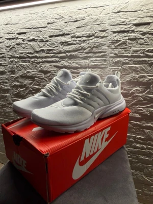 Nike air prestos  - Säljer ett par helvita Nike sneakers med klassisk snörning och meshdetaljer. Skorna har en sportig och clean look med diskret Nike-logga på sidan och tå. Perfekta för dig som gillar stilrena och bekväma sneakers.