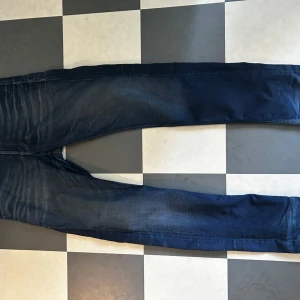 Jack and Jones  jeans - Säljer ett par Jack and Jones jeans i mörkblå tvätt. Modellen är slim och har klassiska fem fickor, snygga slitningar och raka ben. Perfekta för dig som gillar en smalare passform och stilren look. Jeansmaterialet är mjukt och följsamt.