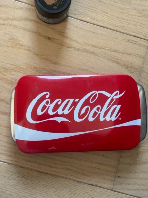 Läppbalsam set i Coca-Cola plåtask - Säljer ett färgglatt set med sju läppbalsam i olika smaker inspirerade av Coca-Cola, Fanta och Sprite. Kommer i en röd metallask med Coca-Cola-logga. Balsamen är i stiftform och har färgglada hylsor med varumärkesdesign. Perfekt för dig som gillar roliga smaker! Vissa är använda, men inte mycket. Andra är helt oanvända och nya.