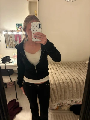 Svart zip hoodie med huva - Säljer en svart hoodie med dragkedja och huva. Hoodien har snörning i huvan, två fickor framtill och ribbade muddar vid ärmar och nederkant. Perfekt för en avslappnad och stilren look. Materialet känns mjukt och bekvämt.