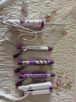 Multistyler hårverktyg - Säljer ett multistyler hårverktyg från Conair i lila och vitt. Setet innehåller flera utbytbara delar för lockar, vågor och volym, inklusive locktänger, spiralstav och vågtång. Perfekt för att skapa olika frisyrer och looks. Sladd medföljer. Köpta i Australien; därav annan pluggtyp. 