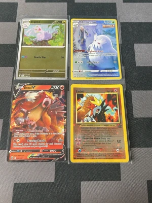 Pokémonkort Sliggoo, Abomasnow, Entei - Fyra Pokémonkort: Sliggoo med grön bakgrund, Abomasnow med blå och vit design, Entei V med röd och orange eldtema samt en klassisk Entei med gul ram. Alla kort har detaljerade illustrationer och ligger i plastfickor. Perfekt för samlare eller Pokémonfans.
