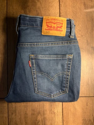 Levi's 512 jeans  - Klassiska blå Levi's 512 jeans i rak modell med fem fickor och snygga kontrastsömmar. Jeansen har den ikoniska röda Levi's-lappen på bakfickan och patch i läder bak i midjan. Perfekta till vardags för en avslappnad men stilren look.