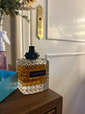 Valentino parfym - Säljer en lyxig parfym från Valentino i en genomskinlig glasflaska med nitar och rutmönster. Flaskan har en svart spraykork och locket finns självklart kvar men tog av de för bilden. Fick i julklapp men kände inte att doften passade mig. Endast använd fåtal gånger