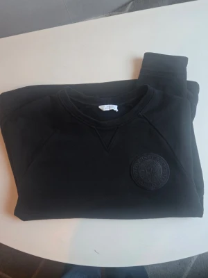 Svart vrsache sweatshirt med rund hals - En stilren svart orginal vrsache sweatshirt med rund hals och ett diskret broderat märke på bröstet. 