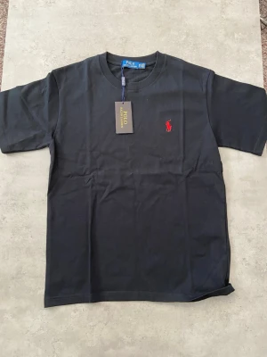 ny Svart t-shirt från Polo Ralph Lauren storlek M - Hej Säljer en svart Ralph lauren t-shirt i nyskick, endast provad. Normal passform i storlek M. Säljes i befintligt skick enligt bilderna.  Skickas samma dag!