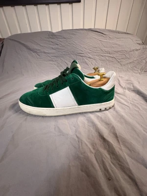 Valentino flycrews  - Snygga gröna Valentina flycrews sneakers i mocka med vit panel på sidan och vit häl. Skorna har klassisk låg profil, vita sulor och gröna skosnören. Perfekta för dig som vill ha en stilren men ändå unik look. Dessa skor säljs ej längre och är svåra och få tag på. Är storlek 42/5 men sitter större i storlek en