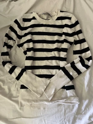 Randig svartvit tröja - Snygg långärmad tröja med breda svarta och vita ränder. Tröjan har rund halsringning och är figurnära i modellen. Perfekt för en stilren och avslappnad look.