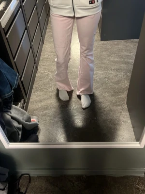 Ljusrosa bootcut jeans - Säljer ett par ljusrosa jeans med bootcut passform och klassiska fickor både fram och bak. Jeansen har hög midja och är tillverkade i ett mjukt denimtyg som ger en skön känsla. Perfekta för dig som vill sticka ut med färg i vardagen!