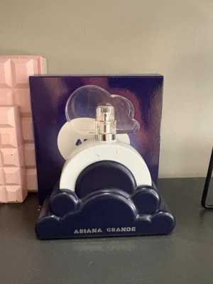Ariana Grande Cloud parfym - Parfymflaska från Ariana Grande i modellen Cloud. Flaskan har en unik design med blå och vit molnform och genomskinlig kork. Kommer i en snygg blå förpackning med molnmotiv. Perfekt för dig som gillar trendiga och lekfulla dofter. 80% kvar
